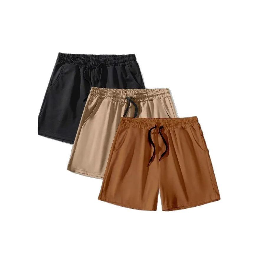 Three men's drawstring shorts in black, khaki, and light brown laid flat, showing loose fit and elasticated fabric.
