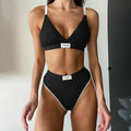 Women's black bikini set with white contrast binding and embroidery detail on the top and shorts.