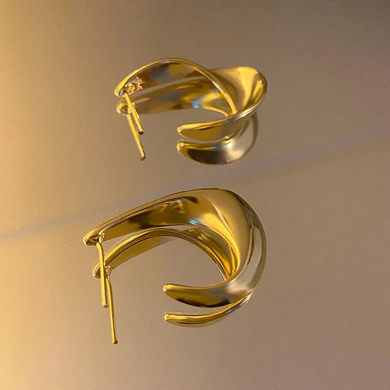 Geometric metal earrings with twisted design and round elements in gold electroplated finish