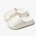 Women's thick-soled EVA beach slippers in beige, shown from the side on a sandy surface.