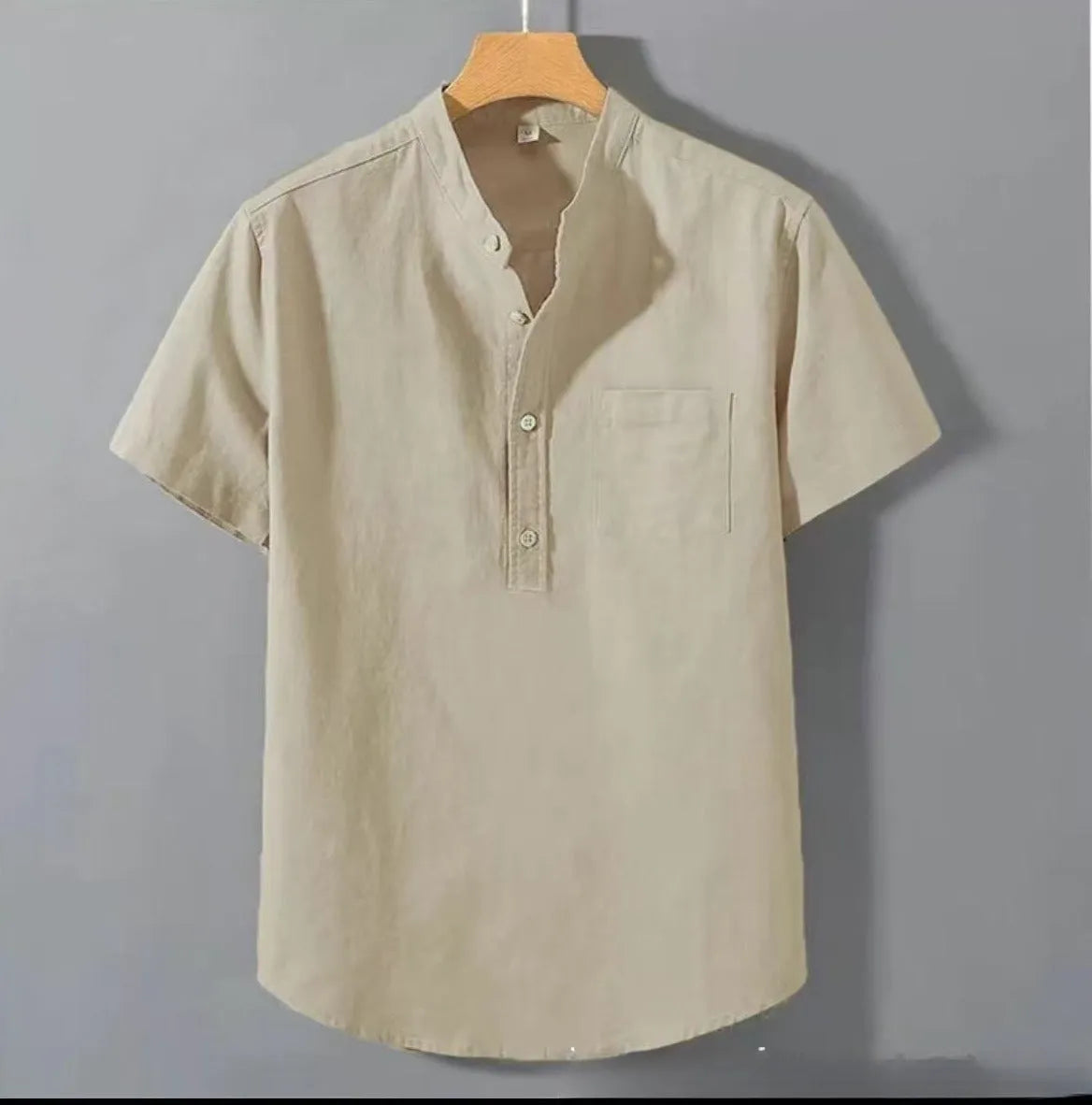 A man's casual beige slub linen shirt with a stand collar and short sleeves, laid flat to show its loose fit.