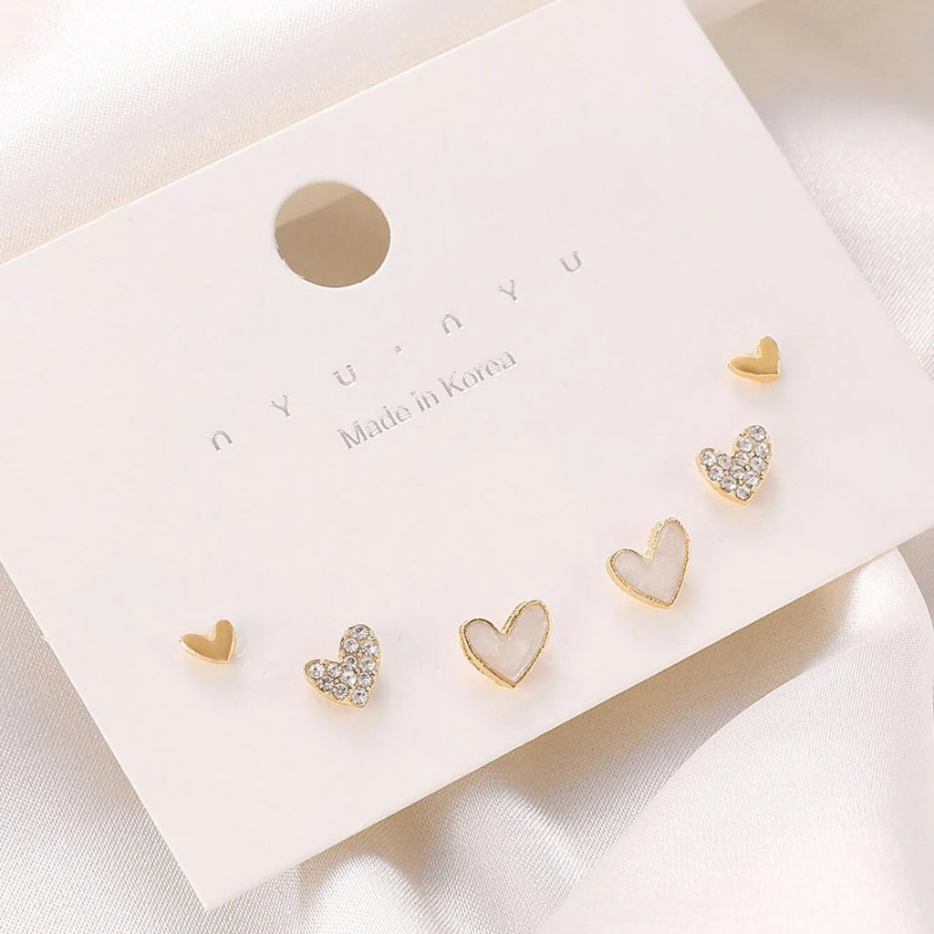 Three pairs of heart shape alloy earrings in gold, black, black white, and pink colours with love design elements