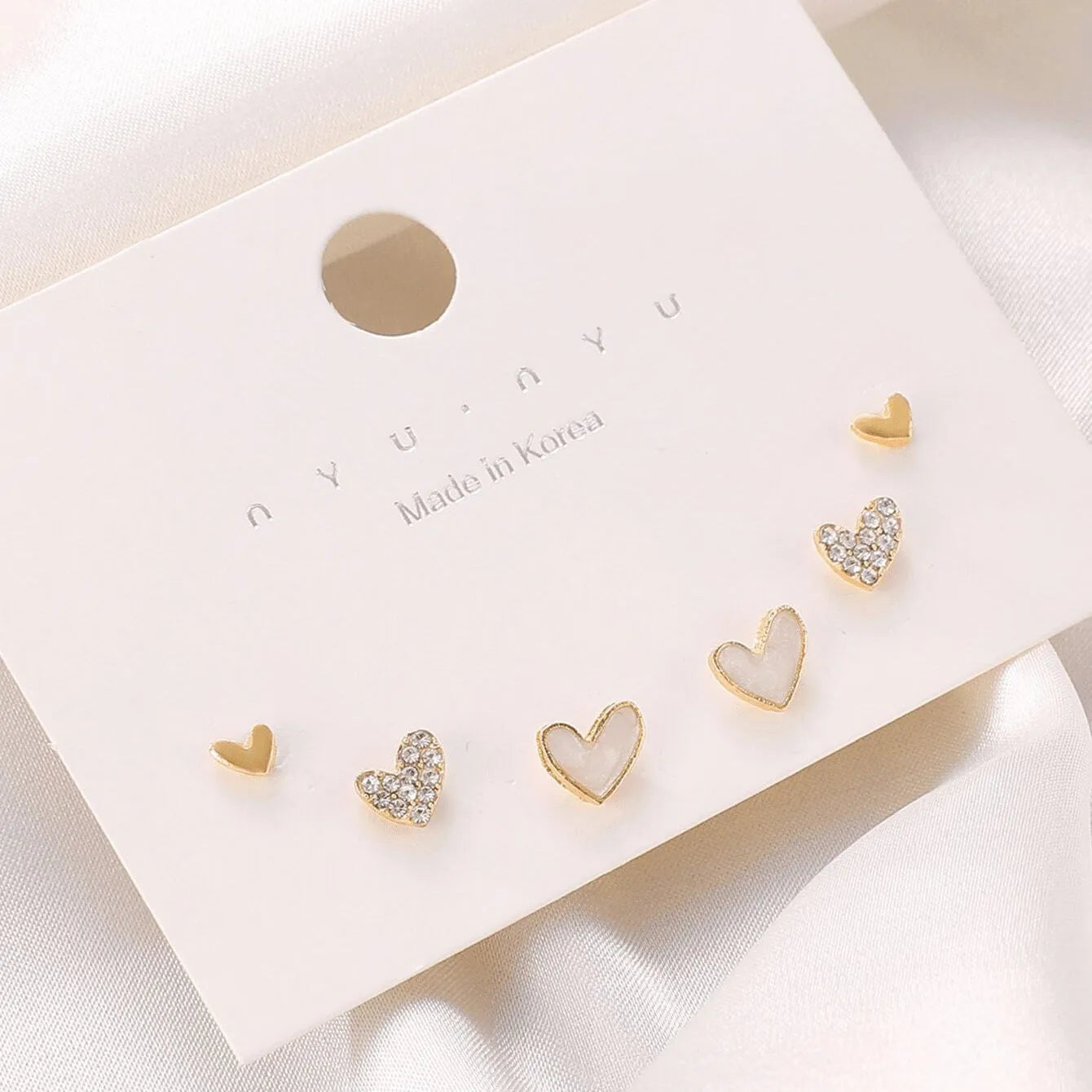 Three pairs of heart shape alloy earrings in gold, black, black white, and pink colours with love design elements