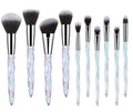 Ten clear crystal-handled foundation brushes with artificial fibre bristles, laid out in a set.