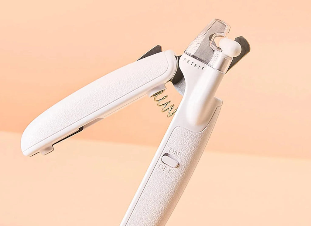White pet nail clipper with LED light on handle and transparent anti-splash guard surrounding the blades.