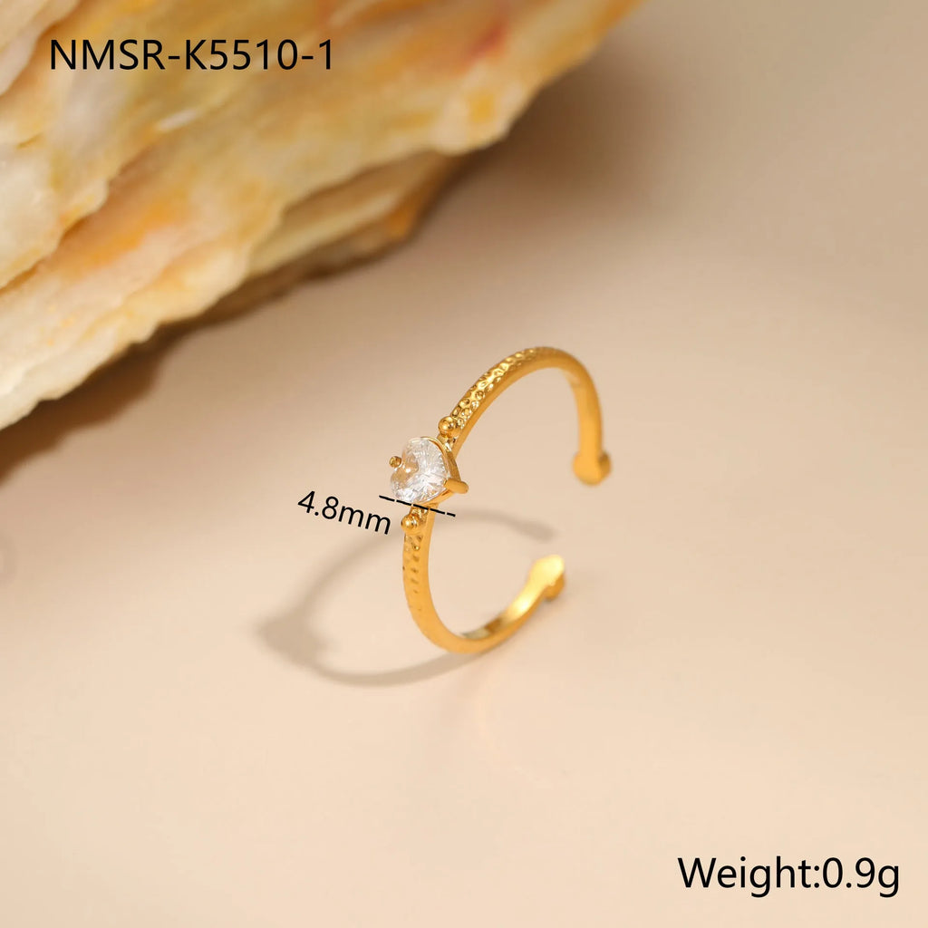 Open-ended adjustable ring with heart-shaped zircon decoration in geometric styling, shown in three colour variations.