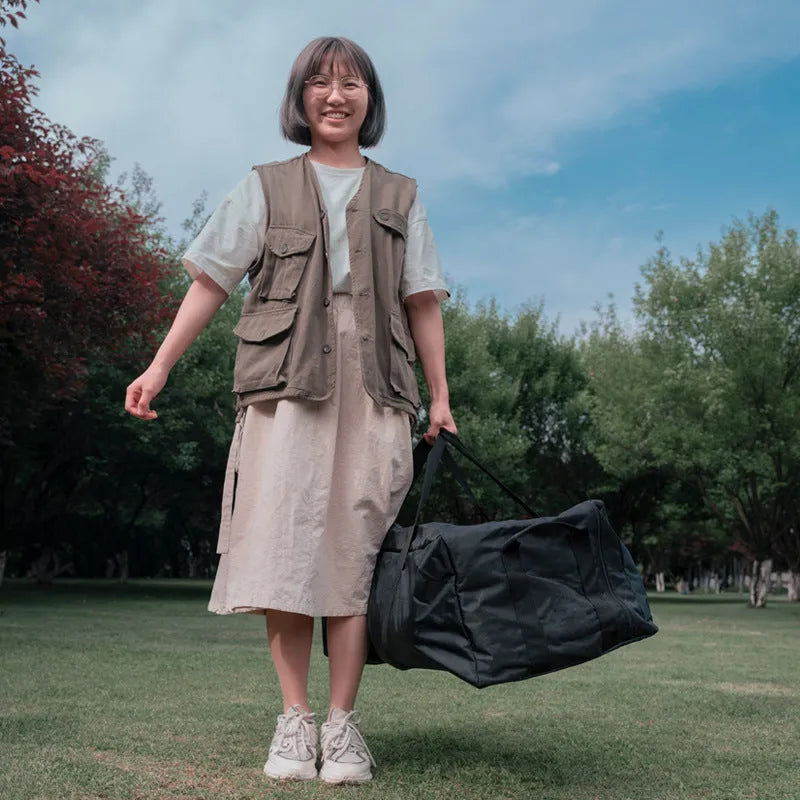 Large black waterproof storage bag with carrying handles, shown next to a folded camping chair.