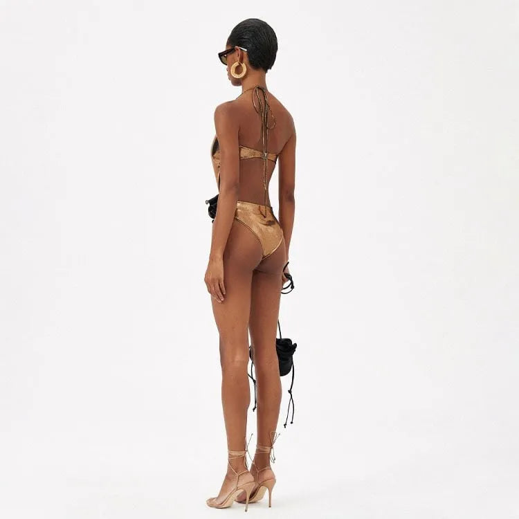 Gold coloured handmade halter neck one-piece swimsuit with hollow-out design on a mannequin.