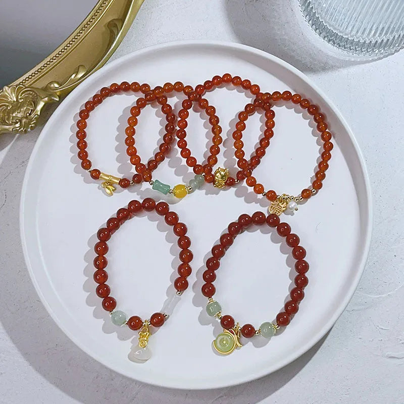 Close-up of a manually crafted red agate bracelet with Lucky Bag and dragon designs on a wrist.