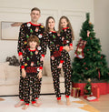 Family wearing matching Christmas pajamas with plaid patterns, including adults, children, and a dog in coordinating sleepwear