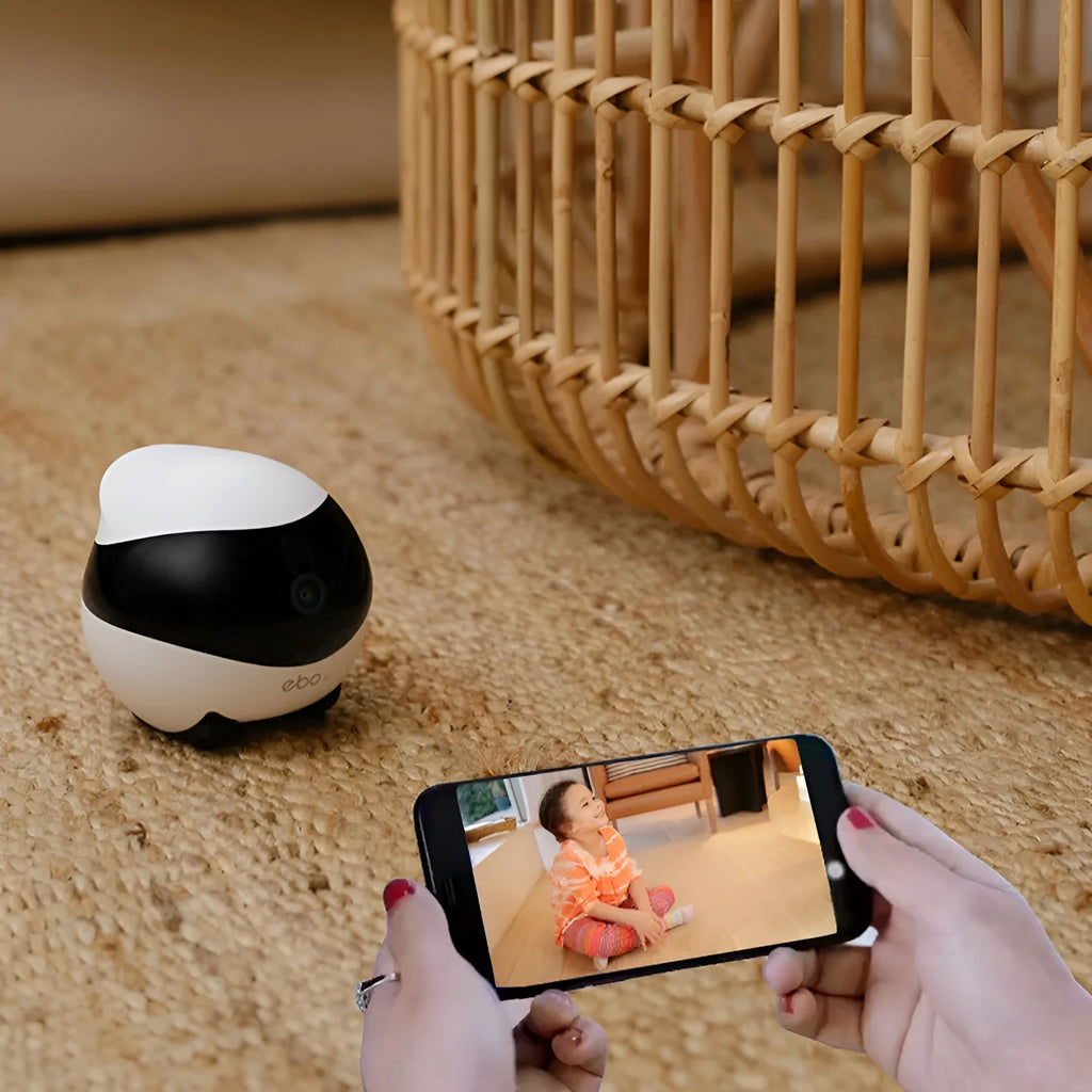 White smart home mobile surveillance robot camera next to its automatic charging docking station.