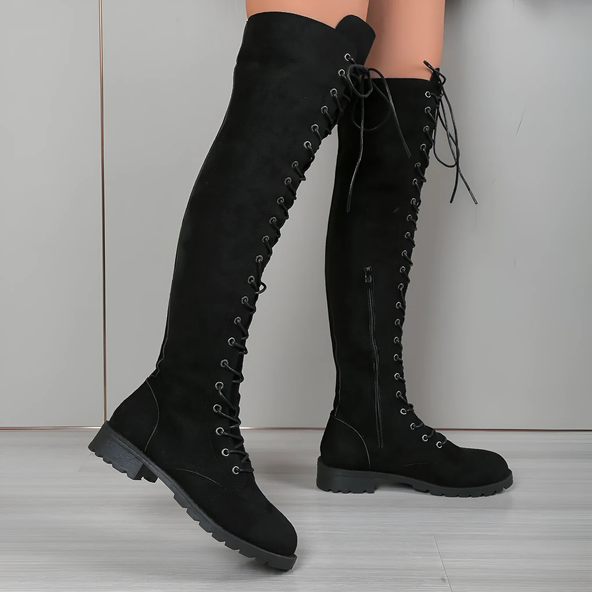 Black lace-up over-the-knee boots with round toe, flat rubber sole, and stitching detail.