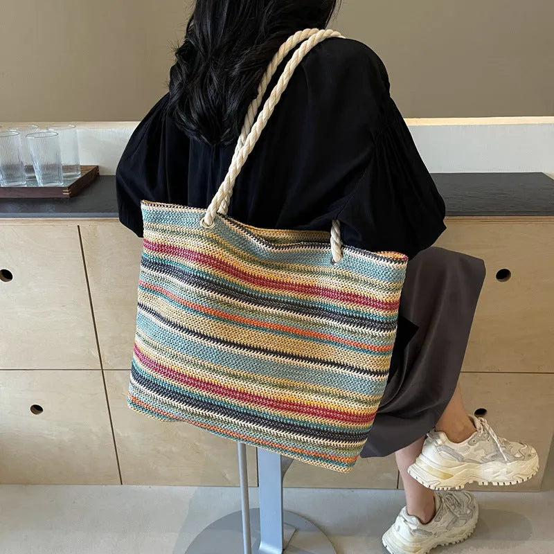 Blue woven straw and nylon shoulder bag with a large main compartment and zippered closure.