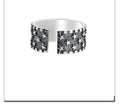 Close-up of an adjustable silver ring with a geometric multi five-pointed star design on a neutral background.