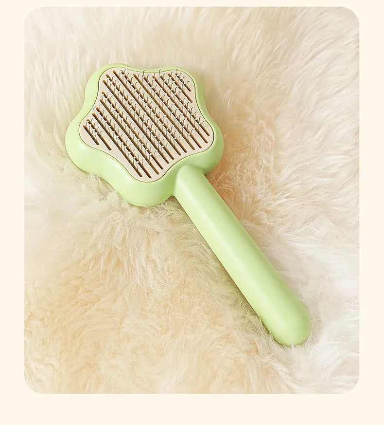 Green stainless steel cat comb with magic wand self-cleaning mechanism showing needle teeth and plastic handle