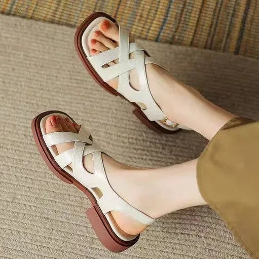 Glossy black patent leather women's sandals with a square toe and cross strap design.