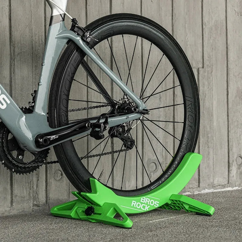 Black and green ABS plastic bicycle parking rack holder mounted on a wall.