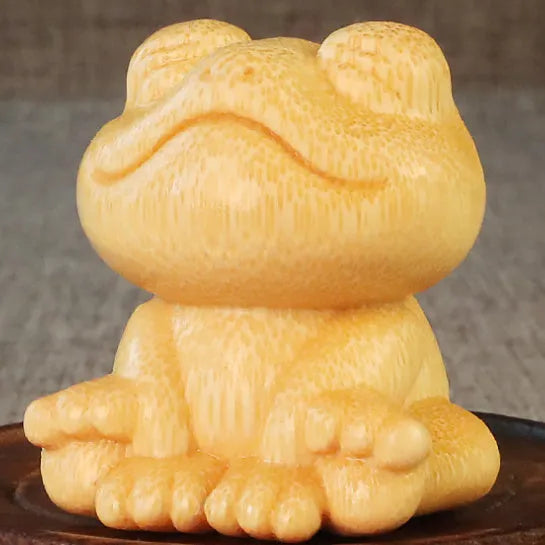 Solid bamboo carving ornament of a smiling frog cartoon character.