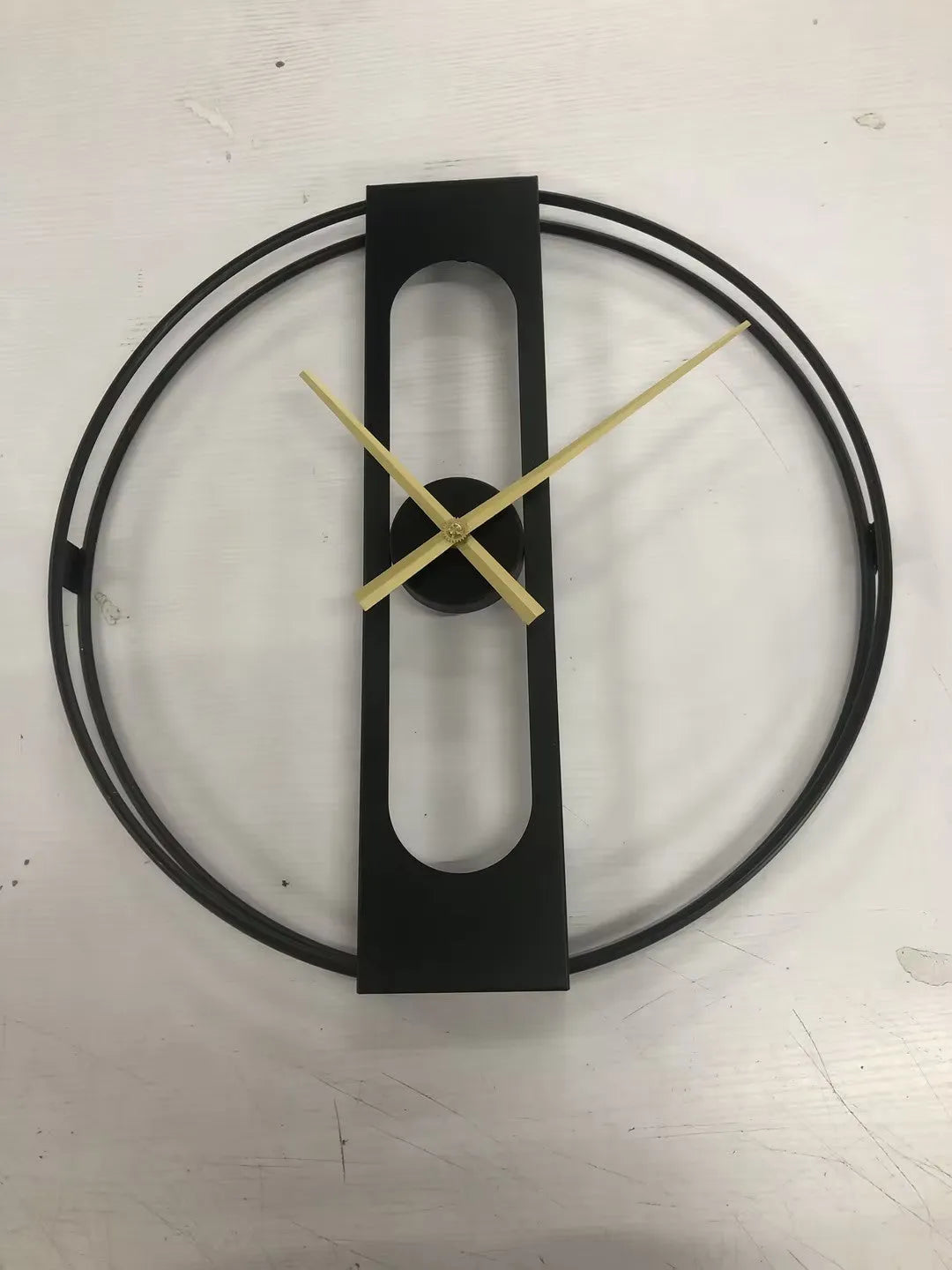 A large 50 cm round metal wall clock on a wall, available in black or gold finish.