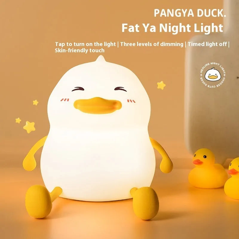 Chubby silicone night light lamp with phone holder on desk, showing soft LED glow and compact 108x104x128mm dimensions