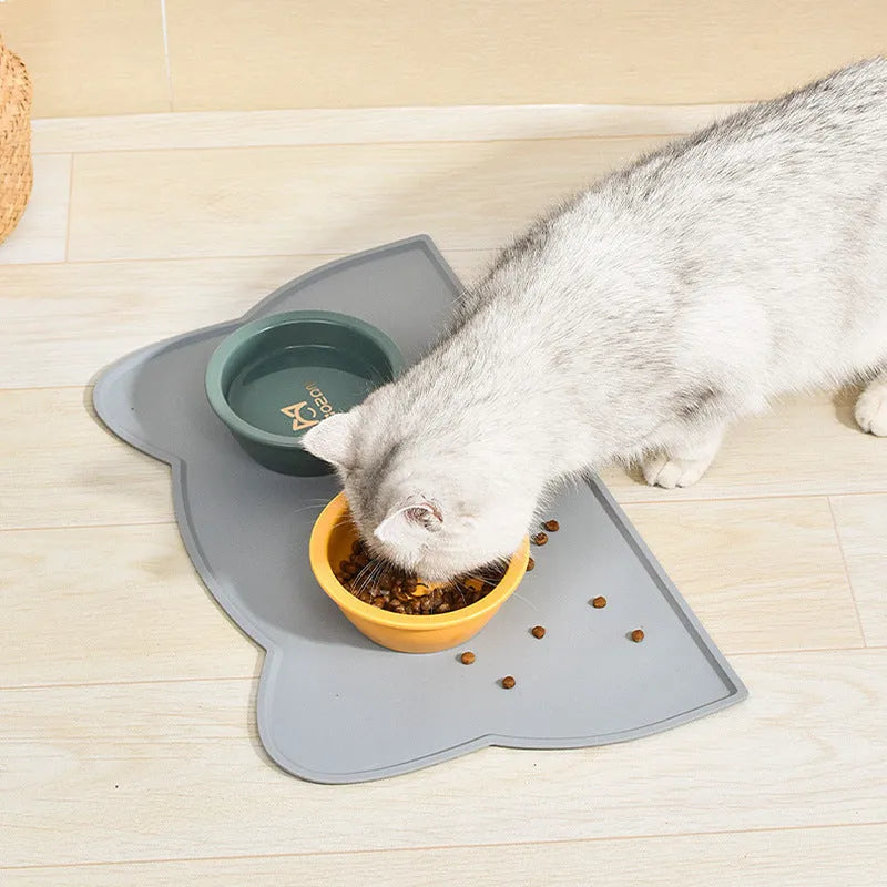 Blue silicone pet feeding mat with cat head shape under food and water bowls