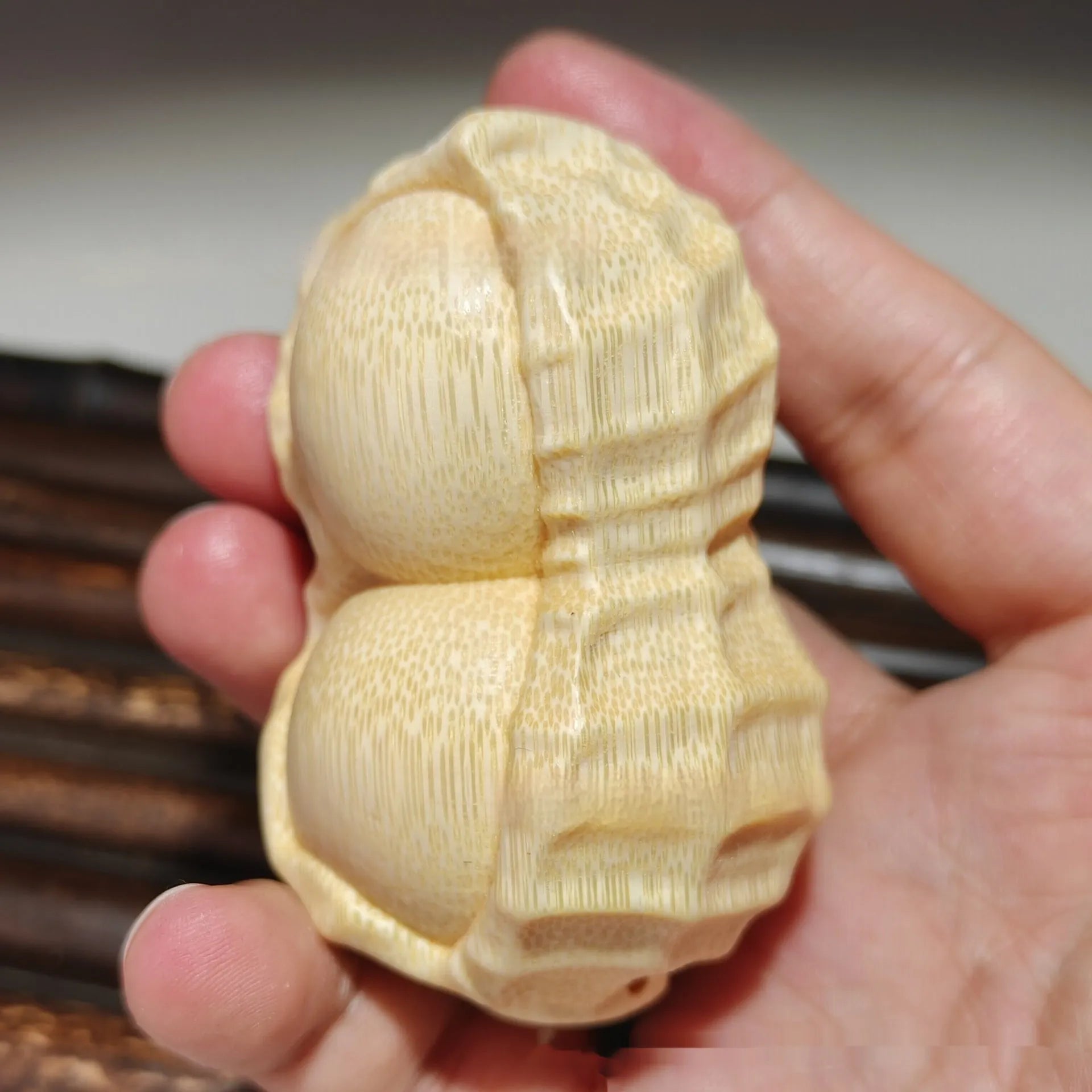 Solid bamboo peanut-shaped ornament with natural wood grain on wooden surface