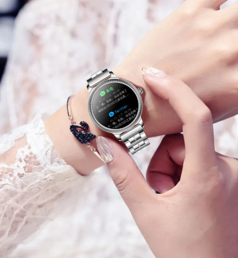 AK38 ladies smart watch with stainless steel Milanese band on a wrist, showing the 1.09-inch colour screen.