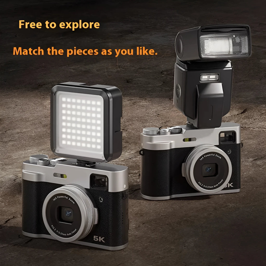 Black 5K HD digital camera with dual lenses and an optical viewfinder on a table with its accessories.