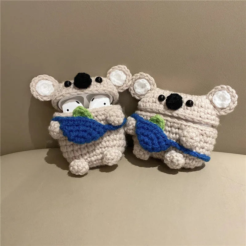 Handmade knitted koala bear backpack cover for AirPods charging case on a table.