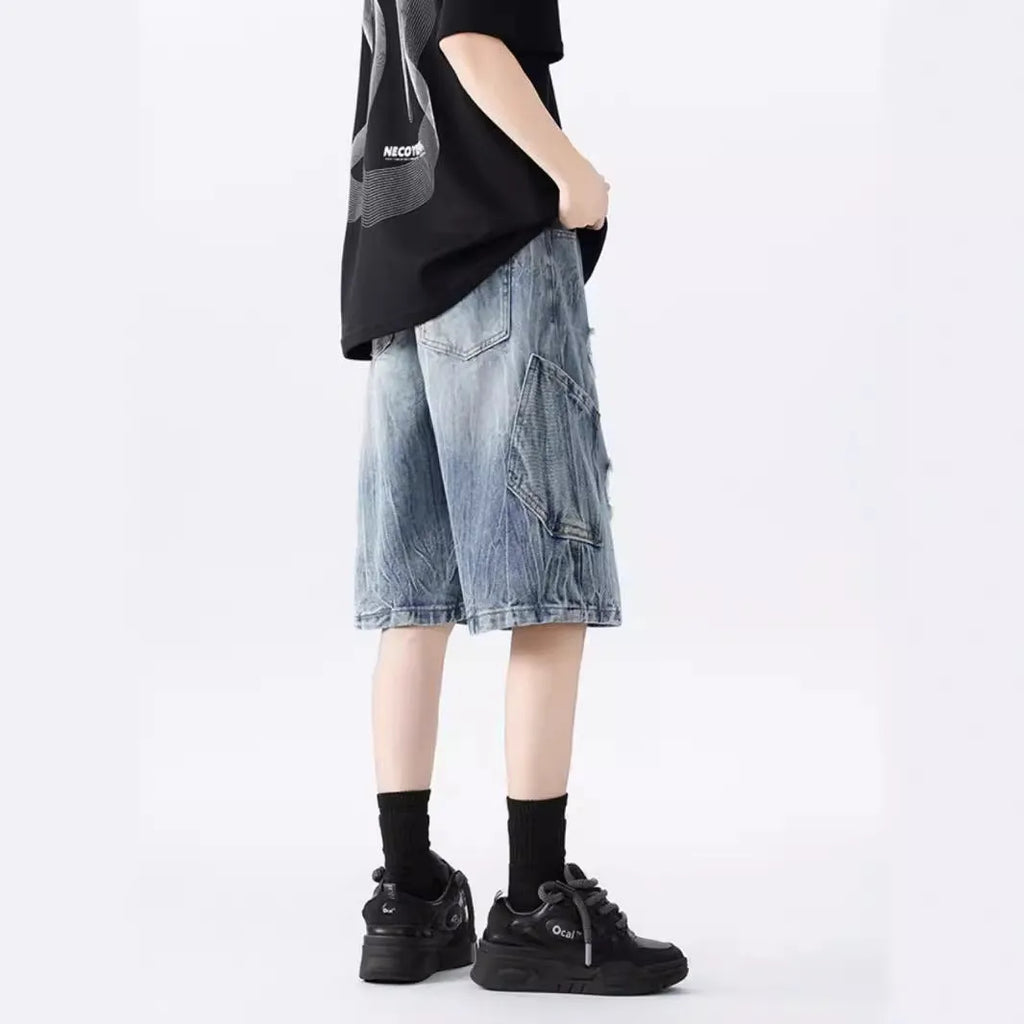 Washed blue denim shorts with ripped detailing on a hanger, showing loose retro fit