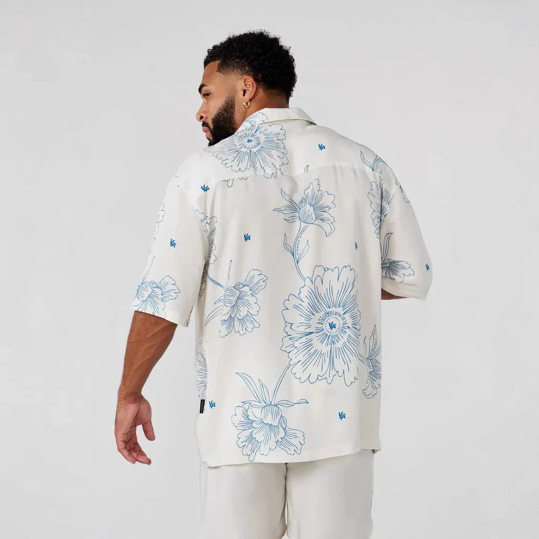 Man wearing a loose fit, short sleeve printed floral top in a neutral colour
