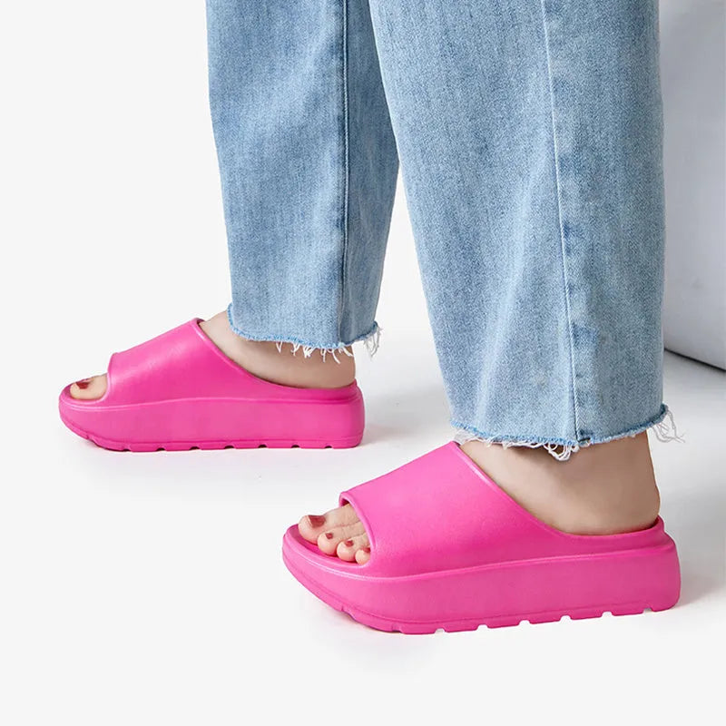 Women's thick-soled EVA beach slippers in beige, shown from the side on a sandy surface.
