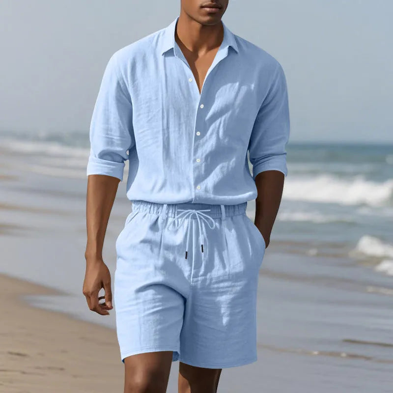 A man wearing a light blue linen long sleeve shirt and matching shorts from the beach suit set.