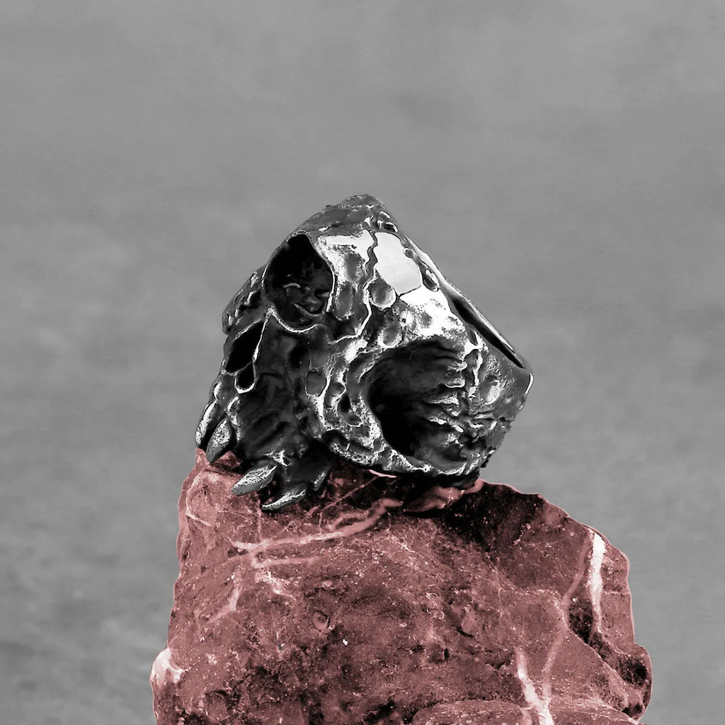 Silver-toned alloy ring with a detailed one-eyed skull design on a black background.