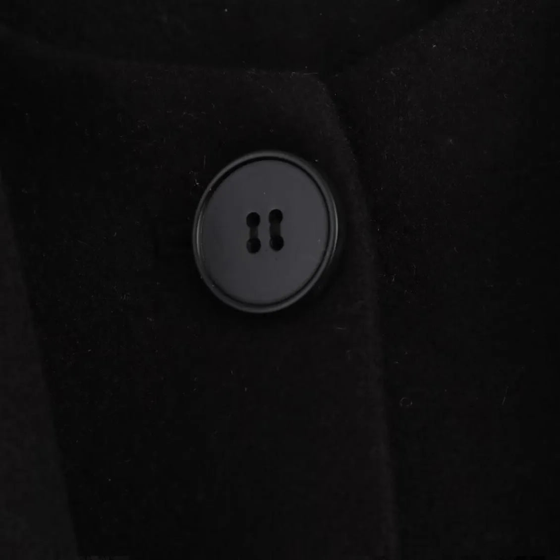 Women's long black polyester overcoat with artificial fur collar and pockets, showing extended length.