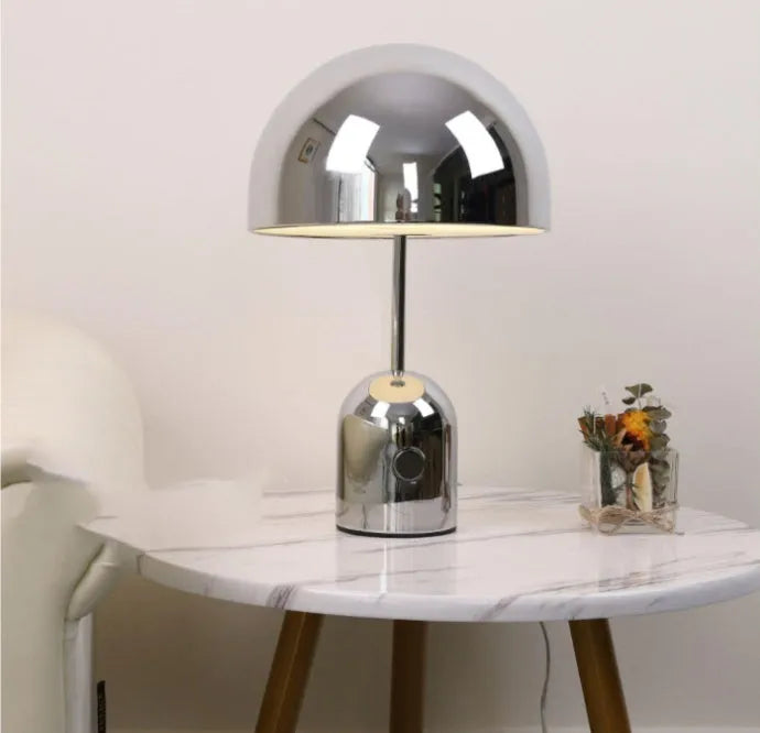 Mushroom-shaped metal table lamp in a rose gold finish on a wooden surface.