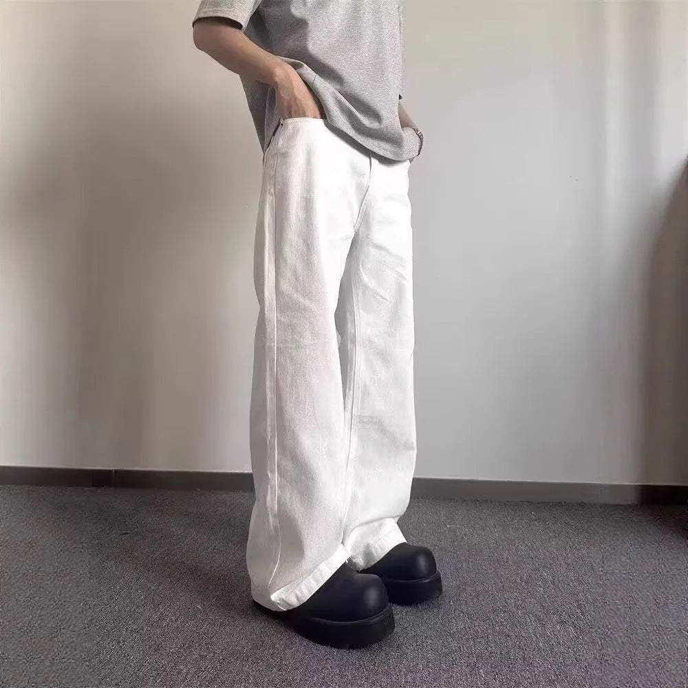 Men's white straight-leg denim jeans with a wide leg opening and a zip fly.