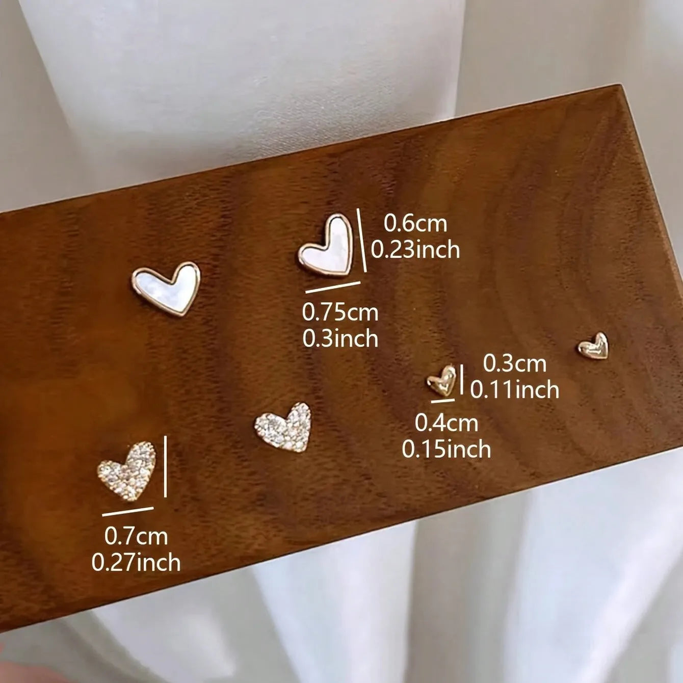 Three pairs of heart shape alloy earrings in gold, black, black white, and pink colours with love design elements