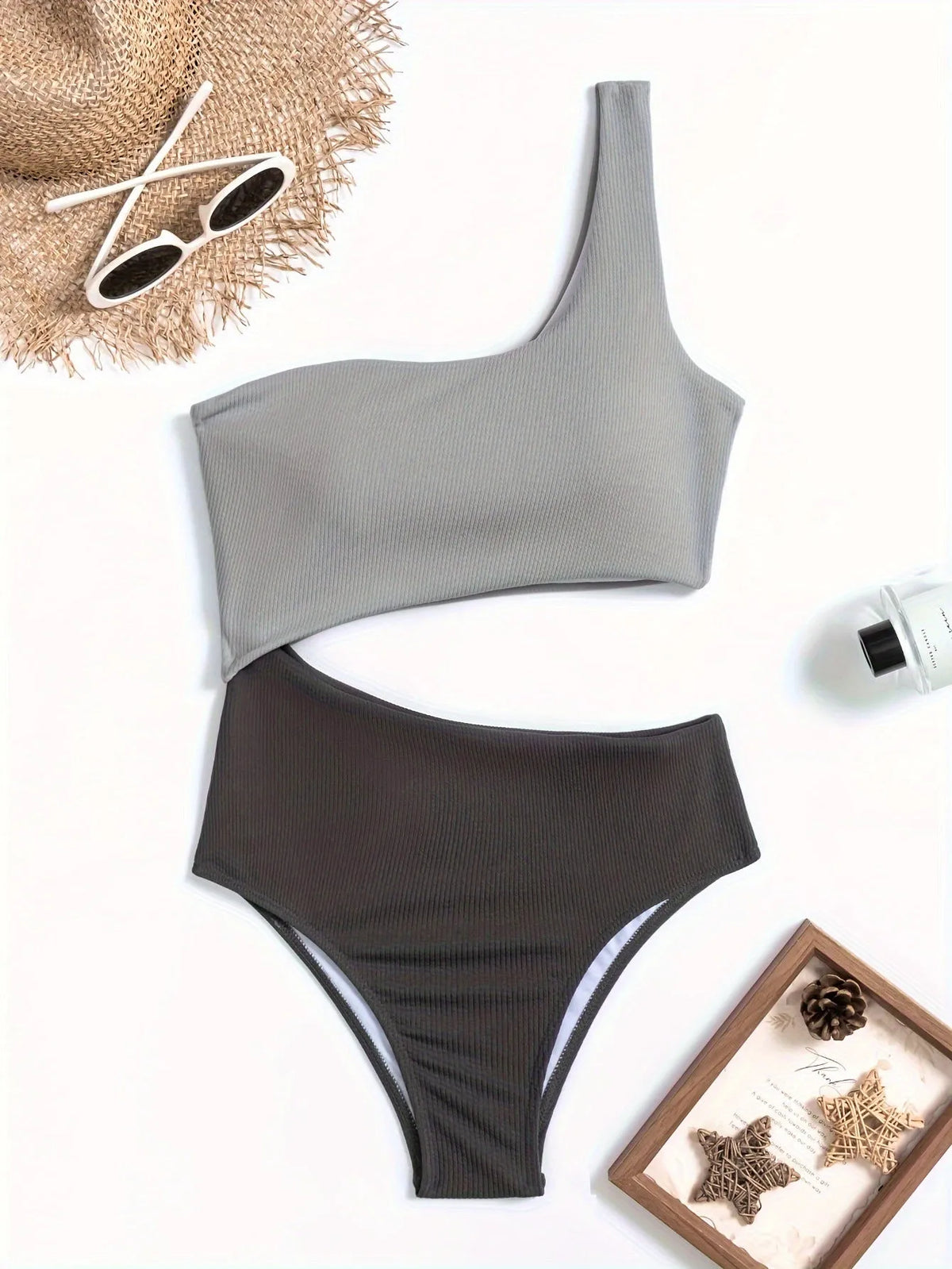 Women's light gray one-shoulder one-piece swimsuit on a neutral background.