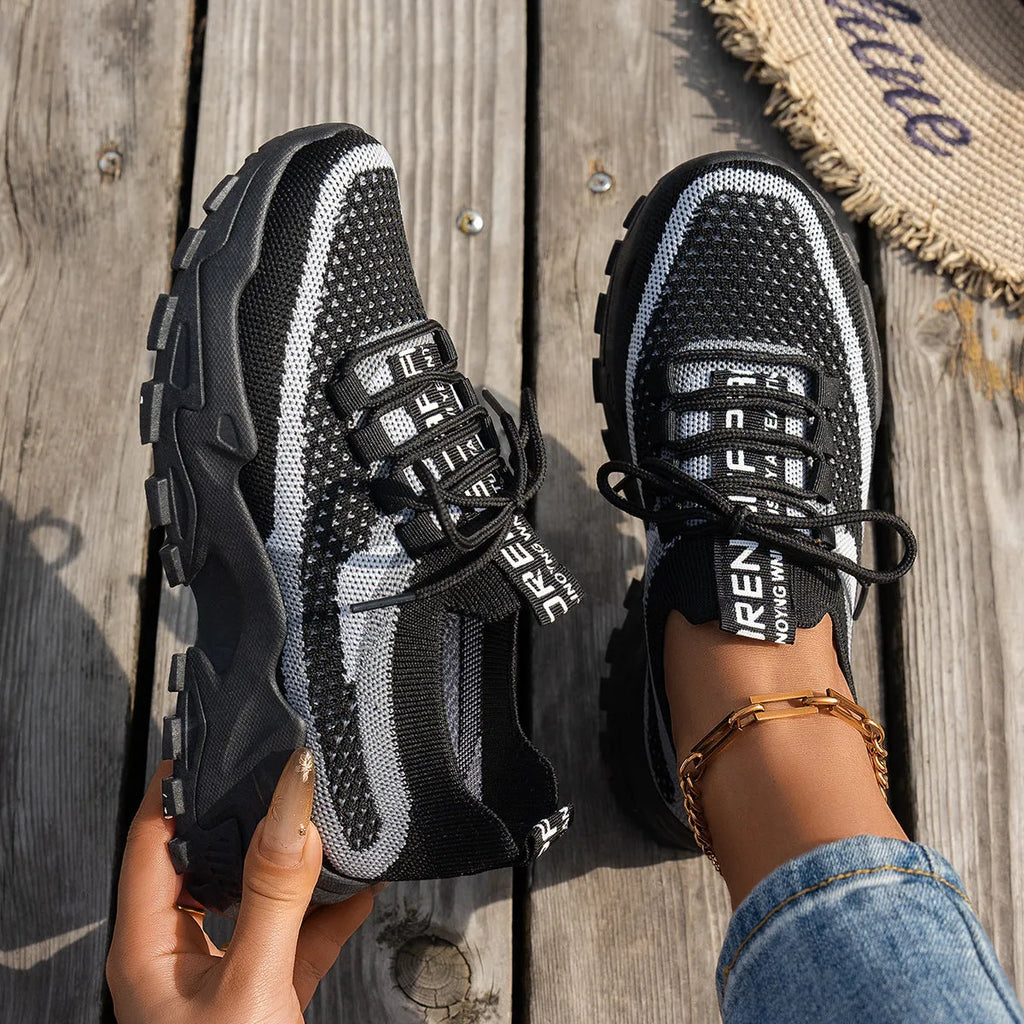 Women's Flyknit mesh sneakers in grey and white with a flat rubber sole and lace-up front.