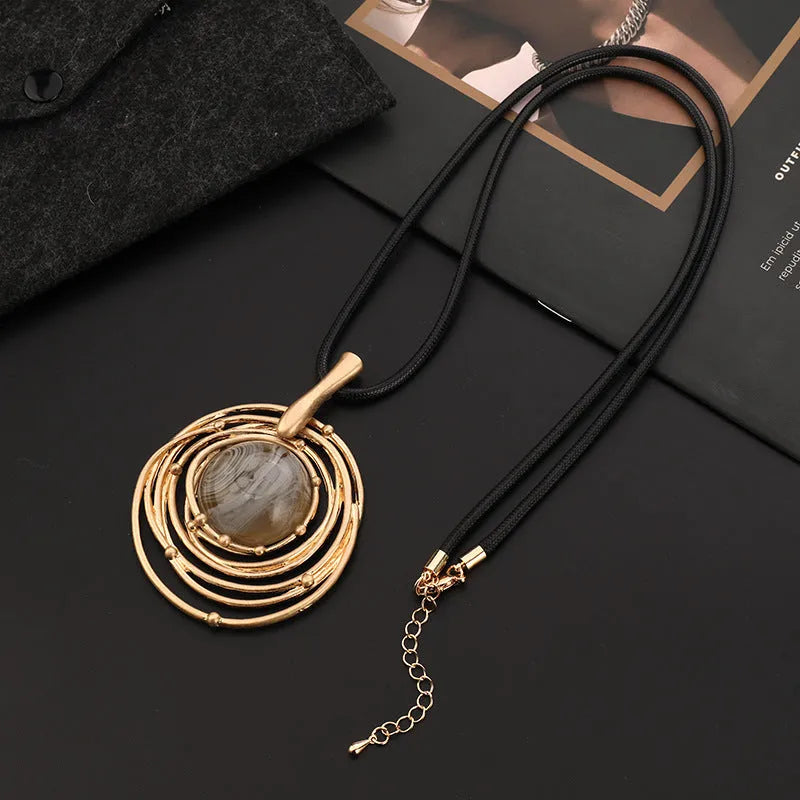 Gold geometric alloy pendant on a brown snakeskin wax rope chain necklace laid flat.