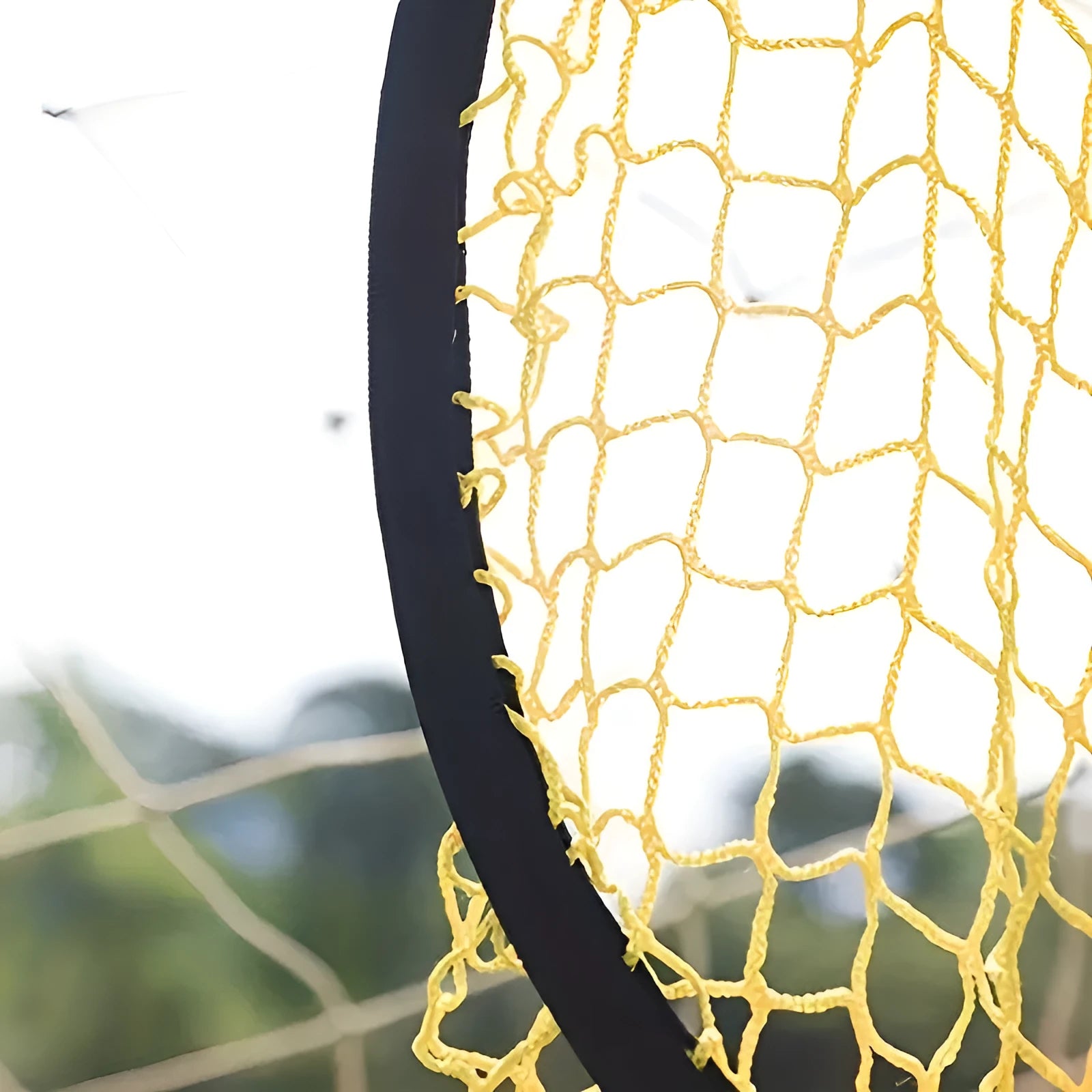 A portable black and yellow soccer training goal net with a steel frame set up on grass.