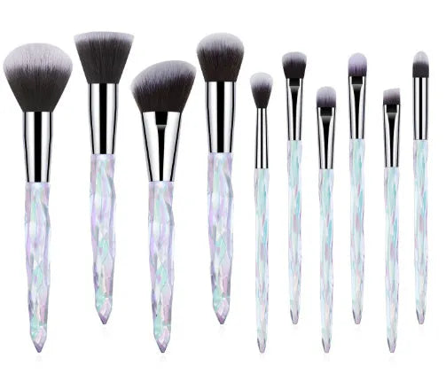 Ten clear crystal-handled foundation brushes with artificial fibre bristles, laid out in a set.
