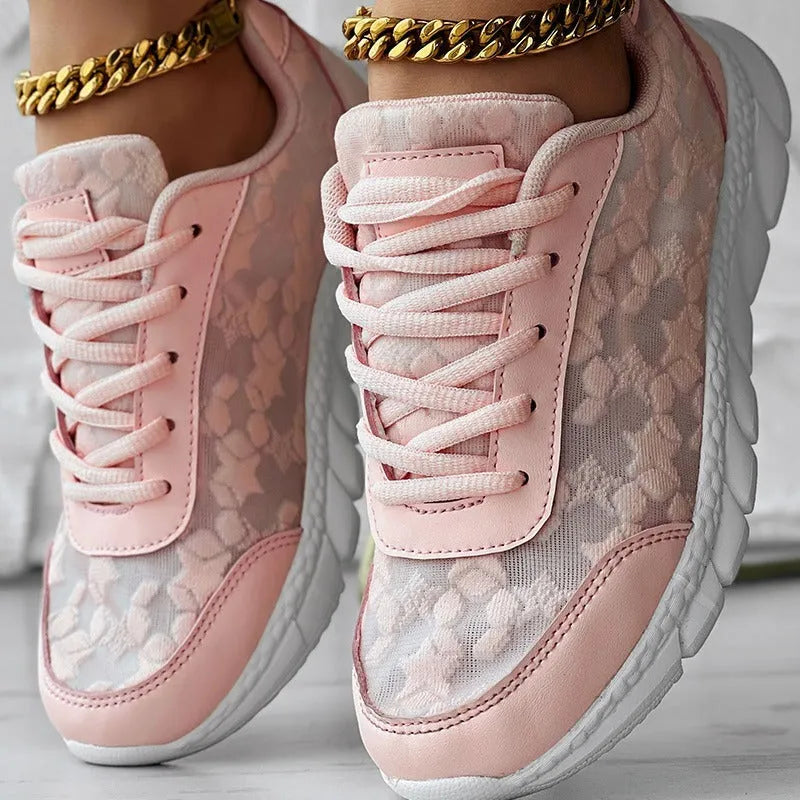 Women's white canvas sports shoes with flat heel and round toe on a plain background.