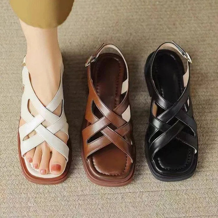 Glossy black patent leather women's sandals with a square toe and cross strap design.