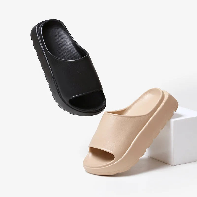 Women's thick-soled EVA beach slippers in beige, shown from the side on a sandy surface.