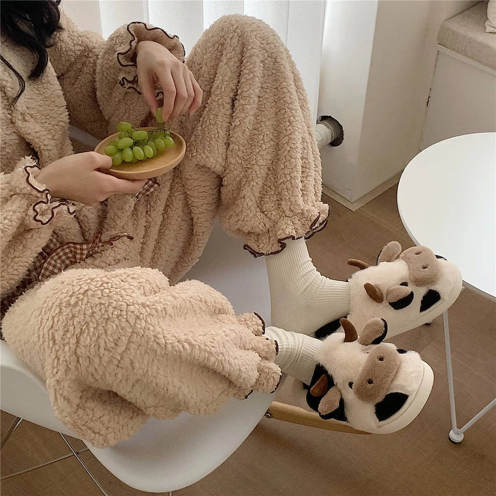 White and coffee coloured cow-themed plush slippers for women with a textured non-slip sole.