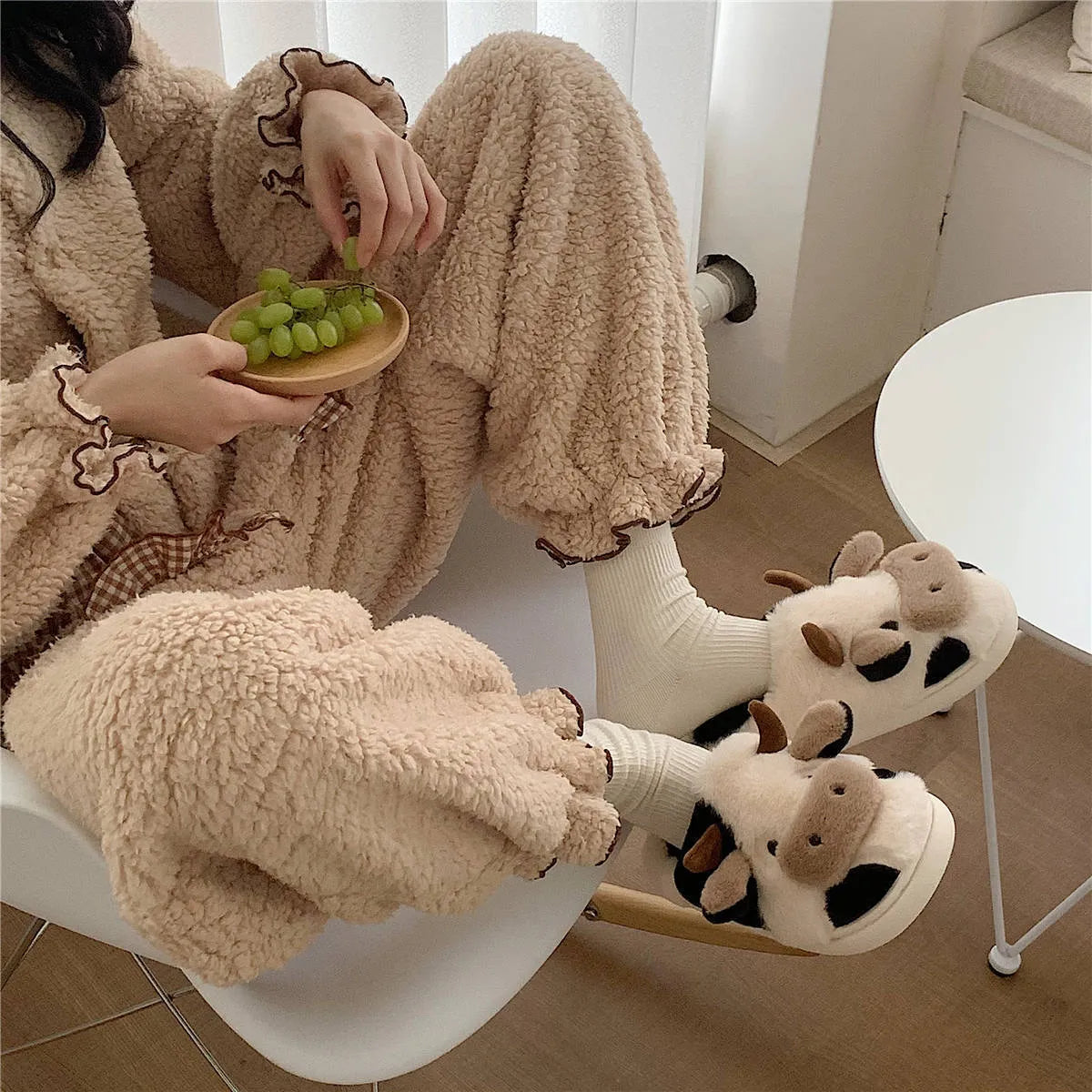 White and coffee coloured cow-themed plush slippers for women with a textured non-slip sole.