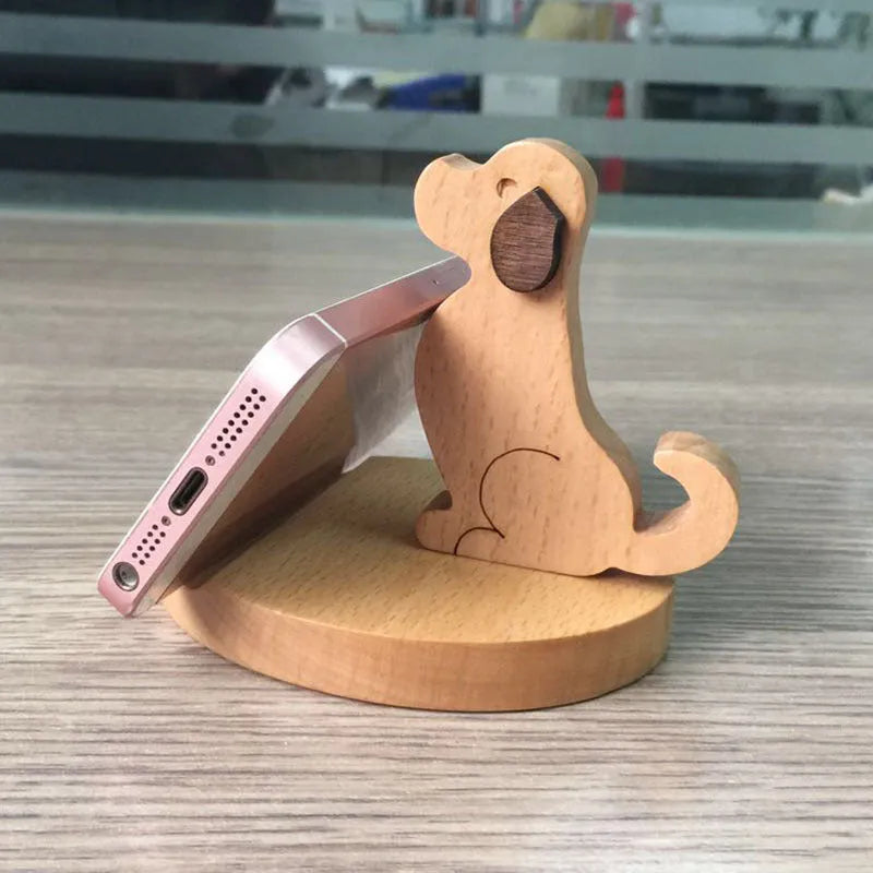 Solid beech wood mobile phone stand with a coin slot, shown alongside resin novelty designs including a dog and elephant holder.