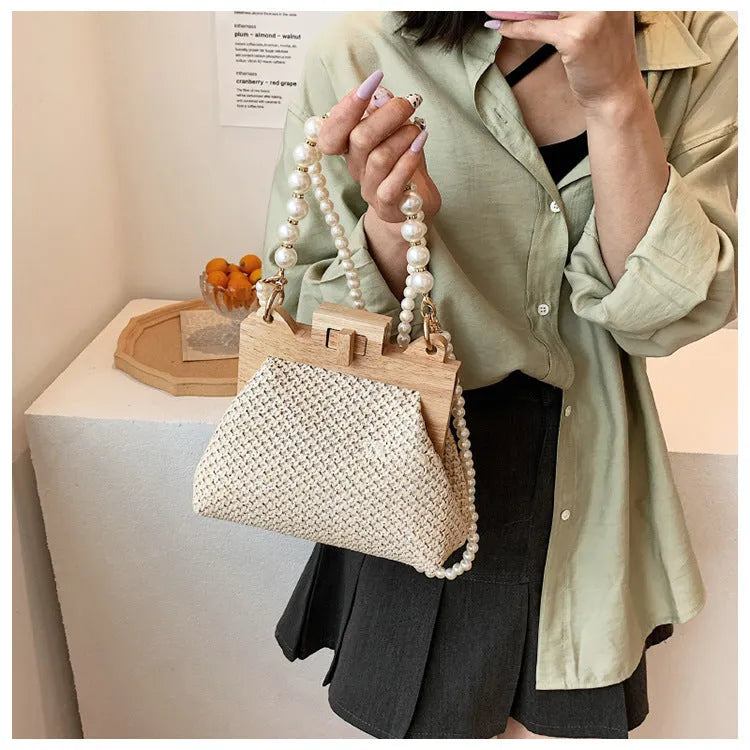 Women's straw woven shoulder bag with pearl chain trim showing internal compartments